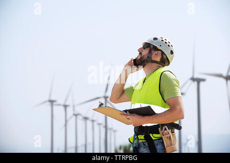 Engineer using smart phone at wind farm Stock Photo