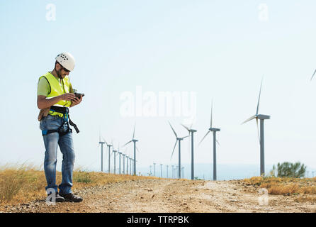 Engineer using tablet computer at wind farm against sky Stock Photo