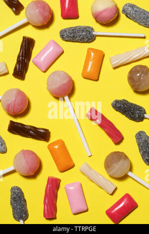 Overhead view of colorful various candies on yellow background Stock Photo