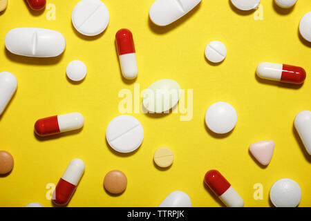 High angle view of various medicines on yellow background