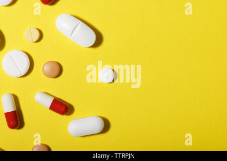 High angle view of various medicines over yellow background