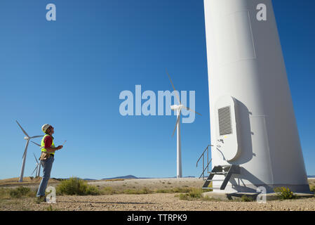 Engineer standing on field against clear blue sky Stock Photo