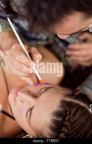 Overhead view of makeup artist painting model's face Stock Photo