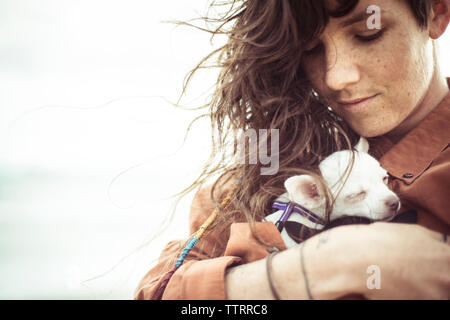 Low angle view of woman holding puppy while standing against sky Stock Photo