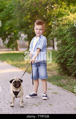 Cute boy with pug dog in park Stock Photo