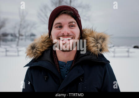 Smiling man looking away while standing against sky during winter Stock Photo