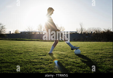 Man practicing soccer on grassy field against clear sky during sunset Stock Photo