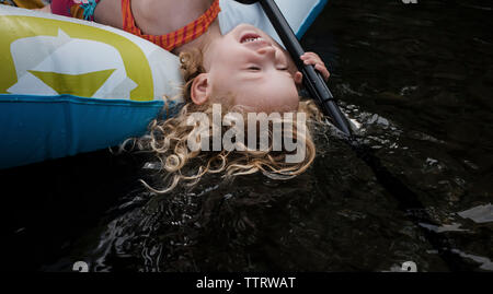 High angle view of happy cute girl lying in inflatable raft on lake Stock Photo