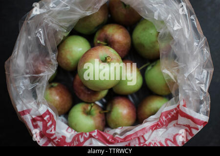 Overhead view of fresh harvested apples in plastic bag on table Stock Photo