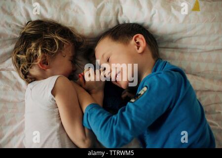 brother and sister laughing and having sibling fun at home in bedroom Stock Photo