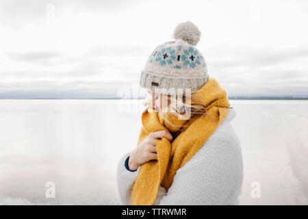 portrait of blonde woman keeping warm at the beach in winter thinking