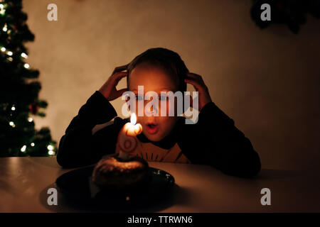 young boy celebrating his 6th birthday with birthday cake and candle Stock Photo