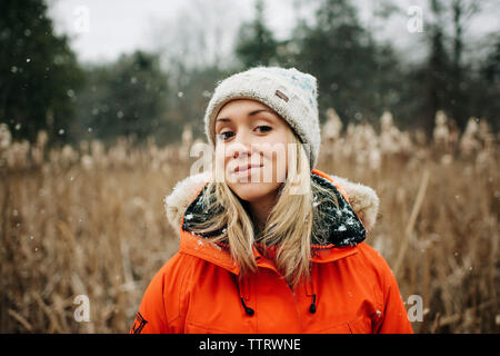 woman smiling in the snow in winter with hat and coat Stock Photo