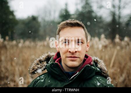 portrait of man standing in the snow in winter coat Stock Photo