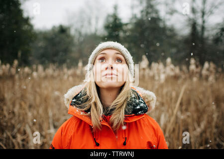 portrait of woman looking up to the sky in the snow in winter Stock Photo