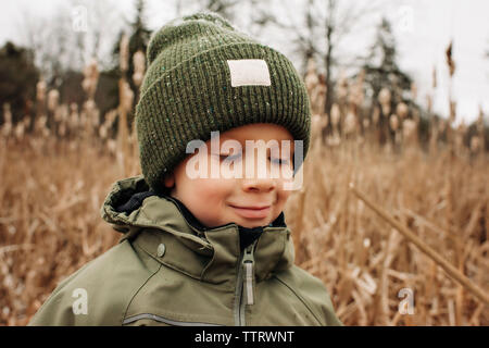 portrait of young boy smiling in winter with hat and coat in the snow Stock Photo