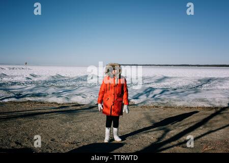 woman in her 60's standing by a frozen lake in winter clothing Stock Photo