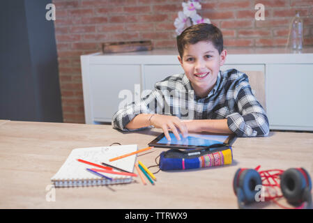 Portrait of smiling boy with tablet computer on table at home Stock Photo