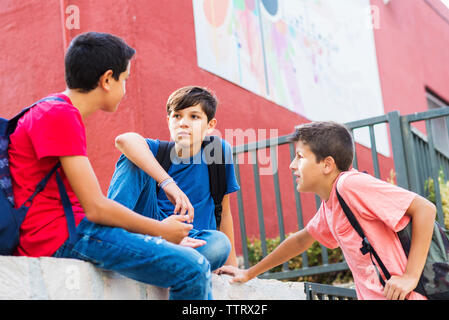 Low angle view of friends talking against school building Stock Photo
