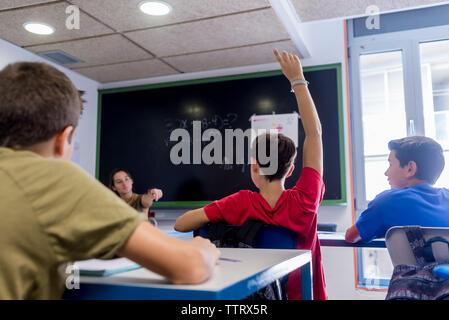 Female teacher interacting with students in classroom Stock Photo