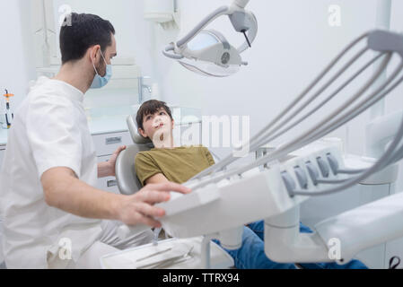 Dentist touching machinery while looking at patient in medical clinic Stock Photo