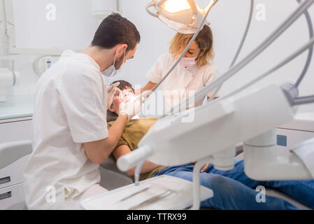 Assistant helping dentist in operating patient at medical clinic Stock Photo