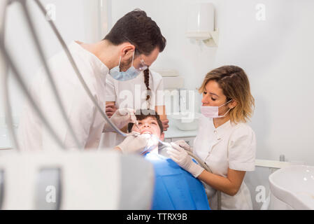 Assistants helping dentist in examining patient's teeth in medical clinic Stock Photo