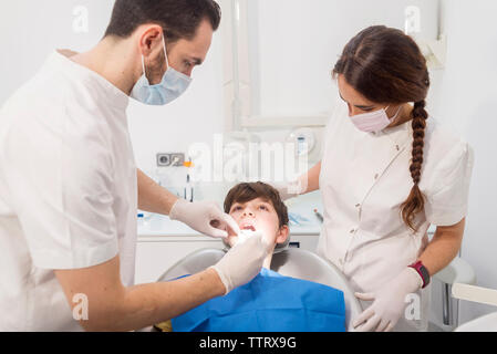 Dentist examining patient's teeth by assistant in medical clinic Stock Photo