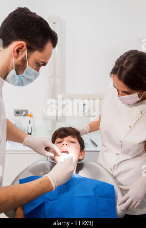 Assistant and dentist examining patient's teeth in medical clinic Stock Photo