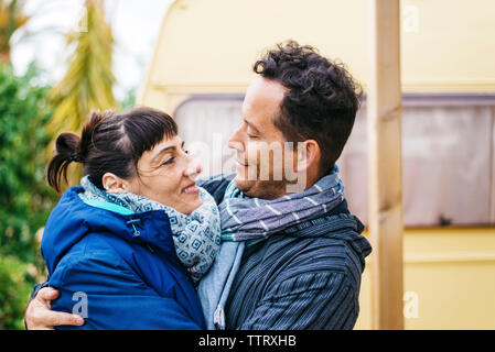 Couple standing outdoors while hugging and looking each other Stock Photo