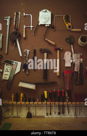 Hand tools hanging on pegboard at guitar workshop Stock Photo