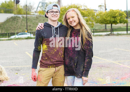 Portrait of happy friends with powder paint standing on footpath at park Stock Photo
