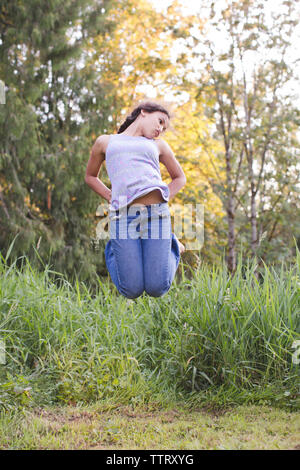 Playful girl jumping in forest Stock Photo
