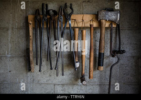 Close-up of work tools hanging on rack at blacksmith shop Stock Photo