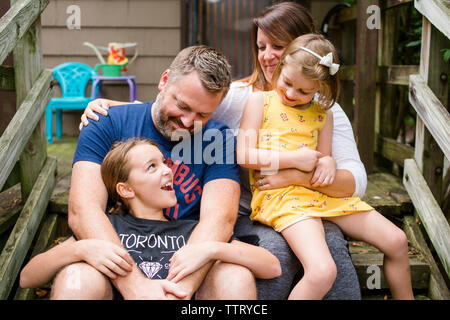 Happy family sitting on steps against house in yard Stock Photo