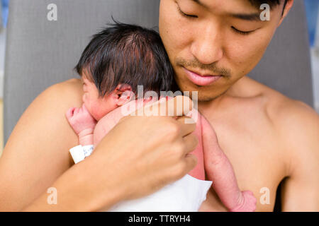 a new father rests peacefully skin-to-skin with his newborn baby girl Stock Photo