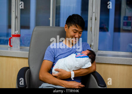 a happy, proud father holds his newborn girl in his arms Stock Photo