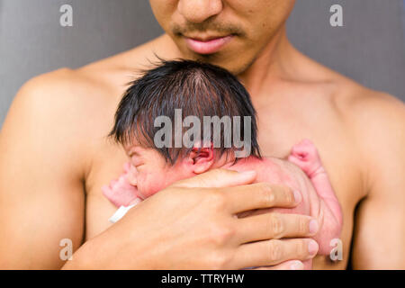 front view of a father holding his newborn in his arms skin-to-skin Stock Photo