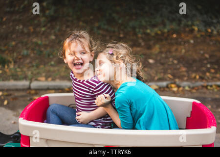 two happy little girls hug in a wagon on a family walk
