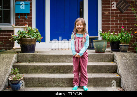 Portrait of a cute girl standing on her front stoop Stock Photo
