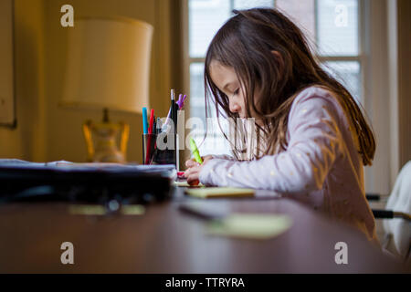 A small girl doing homework at a desk at home Stock Photo