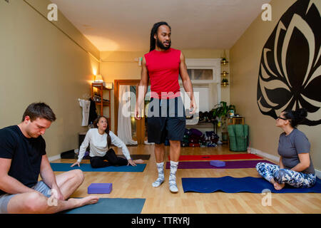 An instructor walks among his students in a yoga class Stock Photo