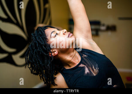 Side view of a beautiful woman, arm raised, relaxing in yoga position Stock Photo