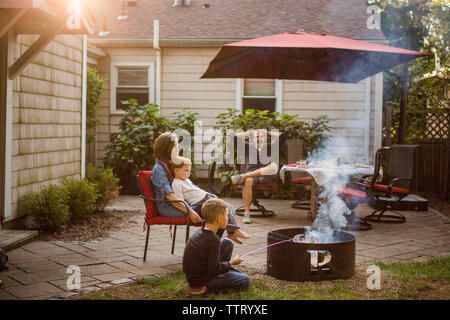a family sitting together in backyard at sunset Stock Photo