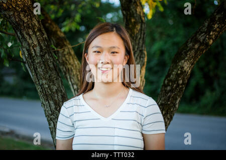 Close-up portrait of a teenage girl against a tree in a park Stock Photo