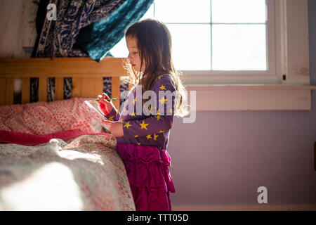 Portrait of a young girl in her bedroom writing in a journal by window Stock Photo