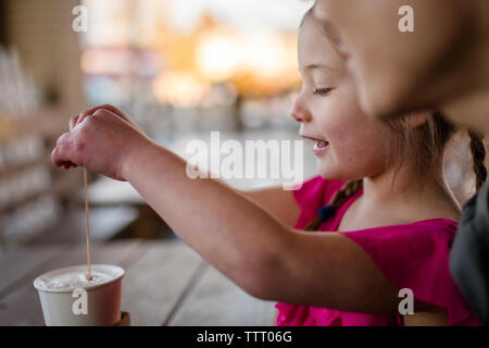 A happy little girl sits with her father at cafe table stirring cocoa Stock Photo