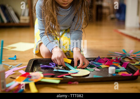 close up view of a child making paper craft on living room floor Stock Photo