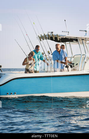 Friends fishing on boat at sea against sky Stock Photo