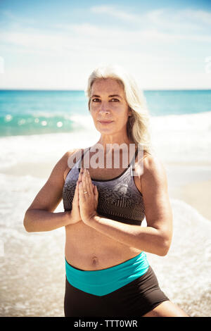 Mature woman in tree pose on beach, portrait Stock Photo - Alamy
